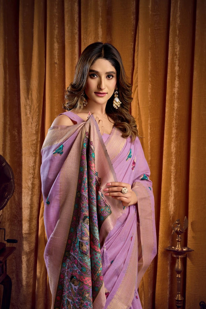 Woman in a pink saree with a colorful border against a brown curtain background